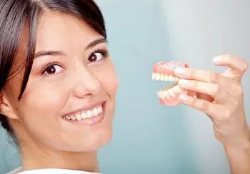 Smiling woman holding a denture